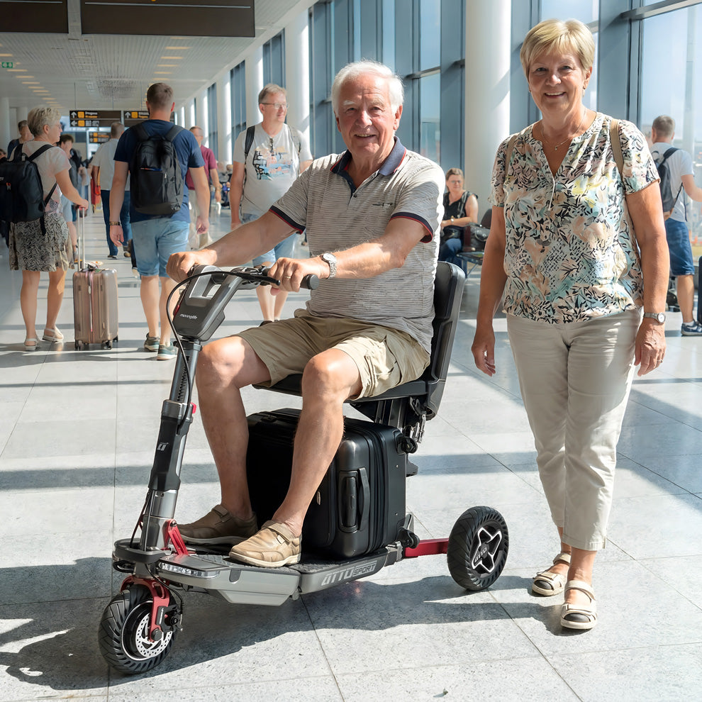 Aktiver Senior fährt selbstbewusst mit dem ATTO Elektromobil durch ein belebtes Flughafen-Terminal.